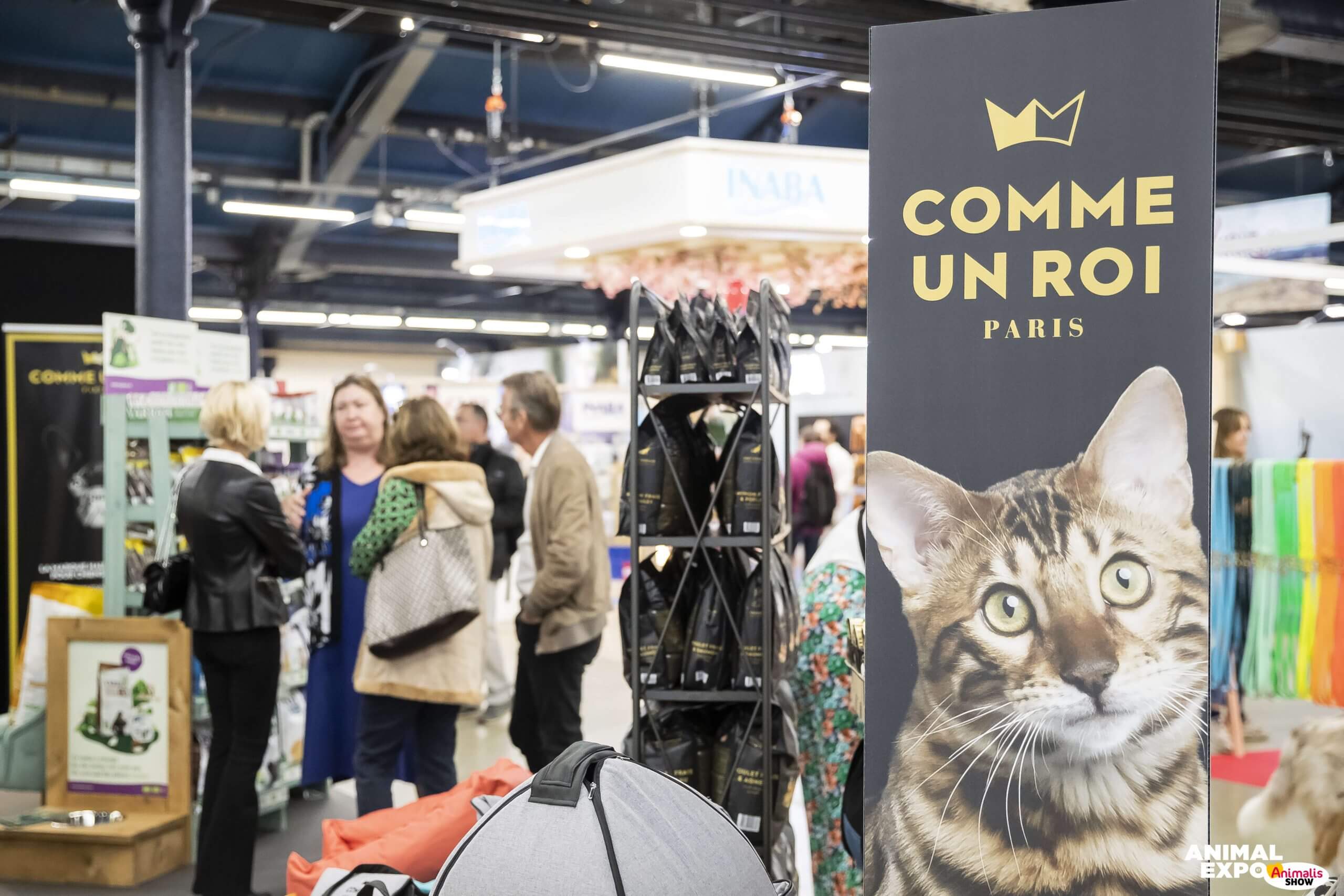 Photo du salon Paris Animal Show d'Exposalons, utilisateur du logiciel événementiel Planexpo. On y voit un kakémono avec une tête de chat et 5 personnes sur l'arrière de la photo, ainsi qu'un stand.
