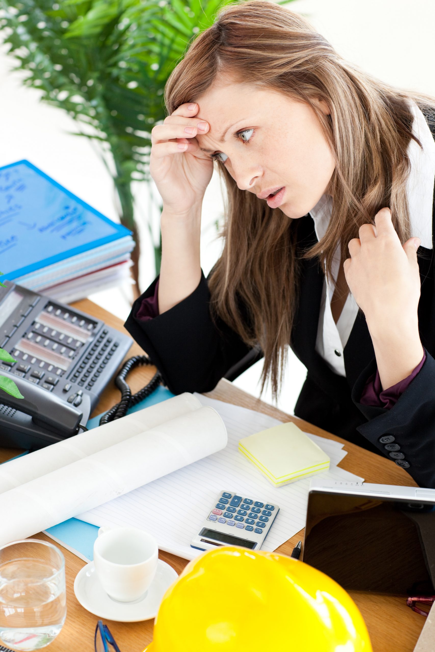 Photo d'une femme qui tient son front et qui a l'air désespéré par la charge de travail associée à la facturation et à la comptabilité de son événement