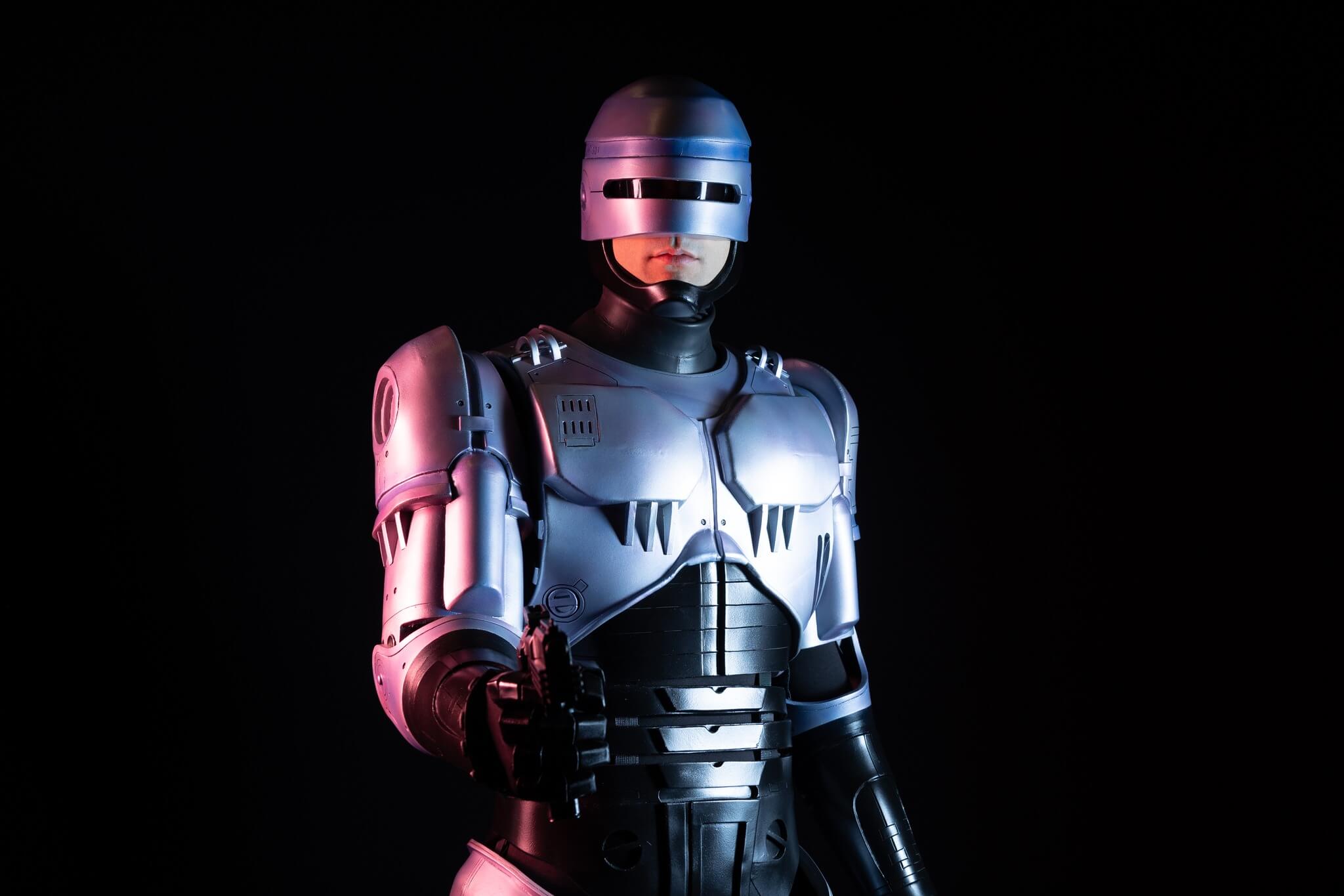 Photo d'un Cosplay déguisé en robot, devant un fond noir.