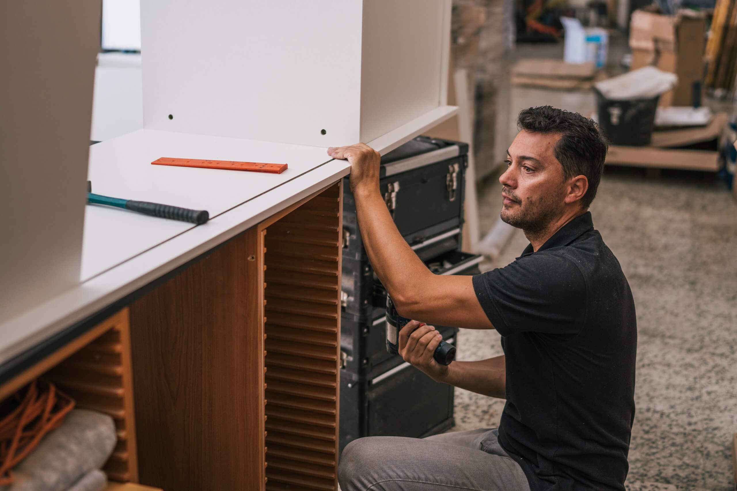 Photo d'un homme à croupie qui est en train de construire et d'installer un mobilier au sein d'un salon événementiel